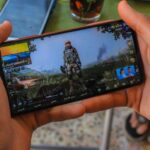 Close-up of a man playing a video game on a smartphone outdoors in Syria.